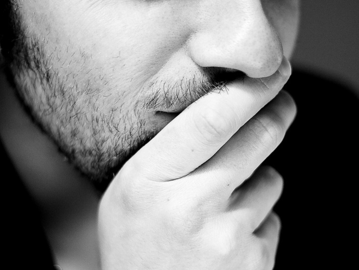 Mann, der die Hand an den Mund hält und sichtlich nachdenkt